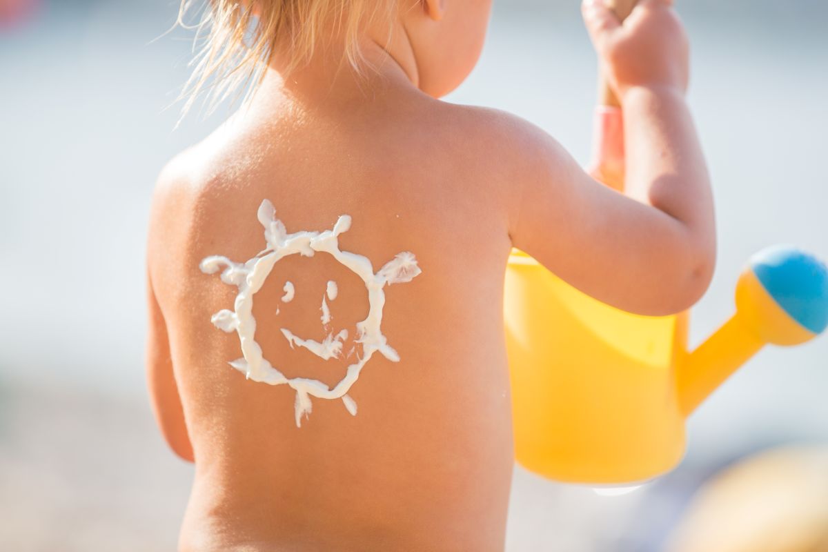 toddler with sun drawn on back in sunscreen